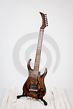 Seven-string electric guitar made of dark wood. Shot on a white background. Background for music and creativity