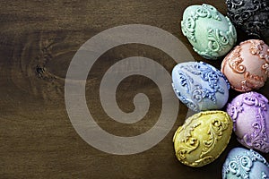 Seven vintage embossed carved vintage Easter eggs on a dark wooden background.