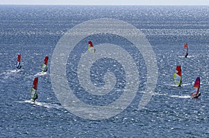 Seven windsurfers are riding on the surface of the dazzling beautiful Mediterranean sea