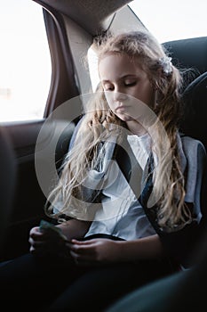 Seven-year charming girl sitting in a children`s car seat