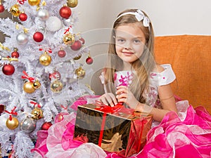 Seven-year girl in beautiful dress sits with a gift in their hands