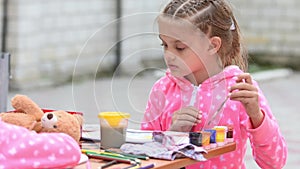 Seven-year girl choose the right color ink drawing in an album, sitting at table with another girl