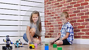 Seven-year-old boy and girl play electronic robots, cars, modern toys on the radio control. new technologies in the