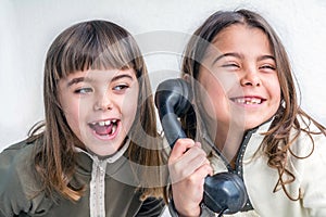 Seven year old girl talking on the old vintage phone and her sis