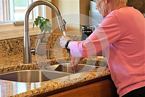 Seventy year old woman washes hands in sink