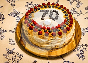 Seventy years celebration birth day home made cake with one candle, rasberries and blackberries on the top