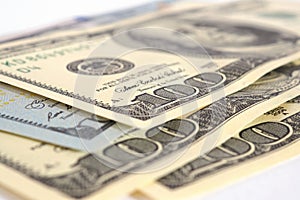 Several American hundred dollar bills lie on a white surface. Close-up