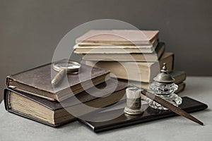 Several of antic books, set of old stationery, wooden pen, inkwell, magnifier close-up, vintage background. Concept of