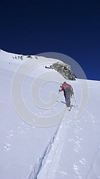 Several backcountry skiers hike and climb to a remote moutain peak in Switzerland on a beautiful winter day