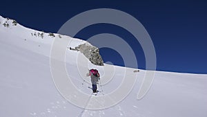 Several backcountry skiers hike and climb to a remote moutain peak in Switzerland on a beautiful winter day