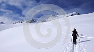 Several backcountry skiers hike and climb to a remote moutain peak in Switzerland on a beautiful winter day