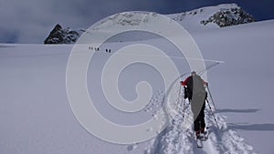Several backcountry skiers hike and climb to a remote moutain peak in Switzerland on a beautiful winter day