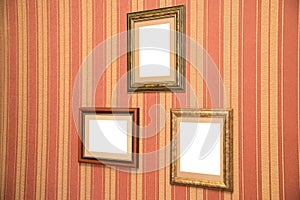 Several beautiful frames for photos of gold on a striped red wall