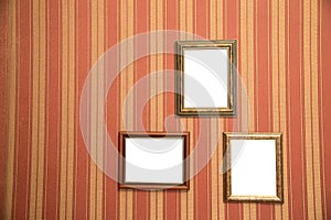 Several beautiful frames for photos of gold on a striped red wall