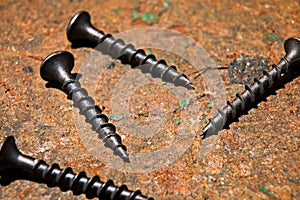 Several black screws on a metal surface