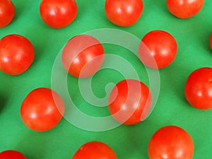 Several bright red cherry tomatoes on a green background