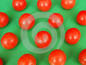 Several bright red cherry tomatoes ordered by green background