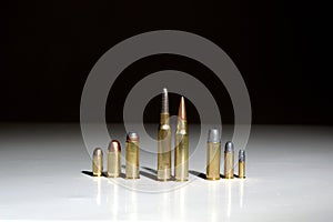 Several bullets of different calibers standing on a white surface with a black background