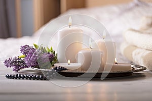 Several burning candles with flower on bedside table in light cozy bedroom interior. Selective focus.