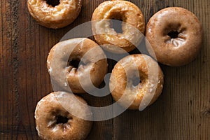 Six cake doughnuts glazed with icing on a stained wood background. Overhead view. photo