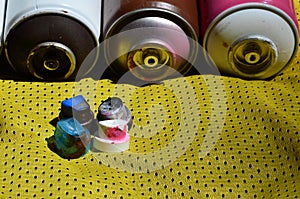 Several caps for used aerosol paint sprayers lie on the sports shirt of a basketball player made of polyester fabric. The concept