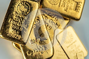 Several cast and minted gold bars on a grey background.