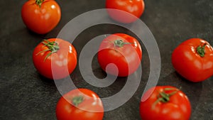 Several cherry tomatoes resting on a dark surface, part of a food recipe