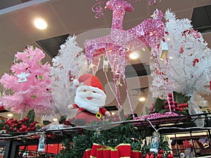 Several Christmas trees and a Santa stuff toy decoration on display