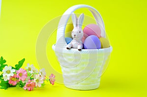 Several colored Easter eggs are on a white basket with a bunny inside