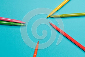 Several colored felt-tip pens on bright blue paper background close up