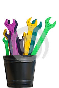 Several colored open end wrenches stand in a black bucket isolated on a white background