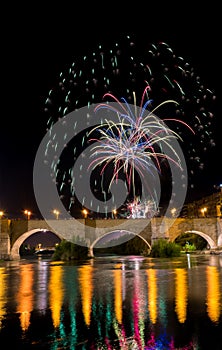 several colorful fireworks exploding in the dark night sky creating amazing light and color effects above the buildings of the