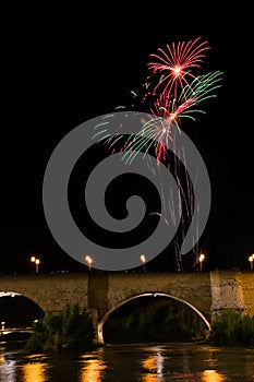 several colorful fireworks exploding in the dark night sky creating amazing light and color effects above the buildings of the