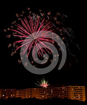 several colorful fireworks exploding in the dark night sky creating amazing light and color effects above the buildings of the