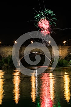 several colorful fireworks exploding in the dark night sky creating amazing light and color effects above the buildings of the