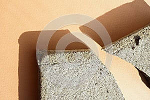 several concrete chips on a beige paper background in harsh light with shadows