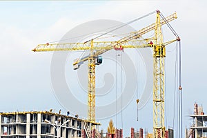 Several cranes and buildings against blue sky. Construction site of hightower structure. Abstract construction