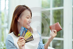 Several credit cards are in the hand of a beautiful Asian woman with the woman out of focus. Happy smiling faces preparing for