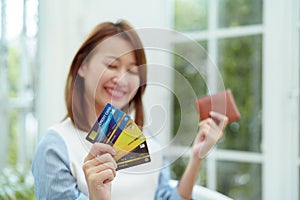 Several credit cards are in the hand of a beautiful Asian woman with the woman out of focus. Happy smiling faces preparing for