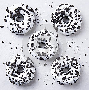 Several delicious fresh hearty black and white doughnuts lie on a white background. Jank food and high-calorie food
