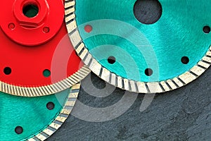 Several diamond cutting wheels of red and emerald color against a background of gray granite