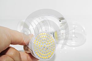 Several different led bulbs and compact fluorescent lamps and the male hand on a light background.