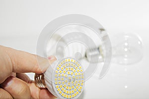 Several different led bulbs and compact fluorescent lamps and the male hand on a light background.