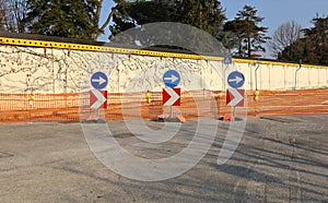 Several directional road signs and warning lights in front of plastic barrier before a temporary closed road.