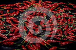 Several dried chilli peppers and crushed peppers on an old s