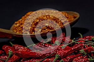 Several dried chilli peppers and crushed peppers on an old s