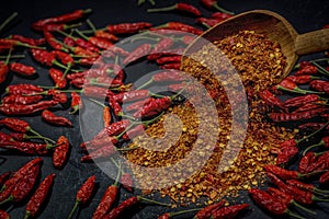 Several dried chilli peppers and crushed peppers on an old s