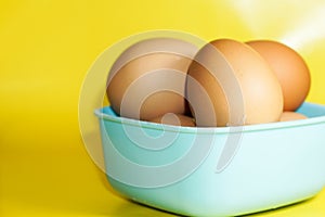 several eggs in a blue container isolated on a yellow background