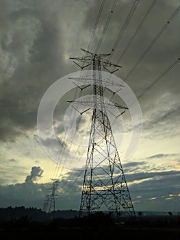 Several electric towers stand with the atmosphere of the sky full of dark clouds