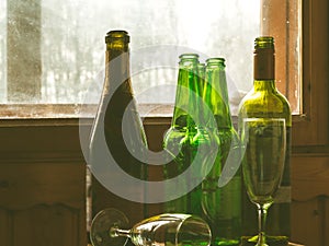 Several empty bottles of alcohol near the dirty window. Selective focus. Alcoholism, drunkenness, loneliness and